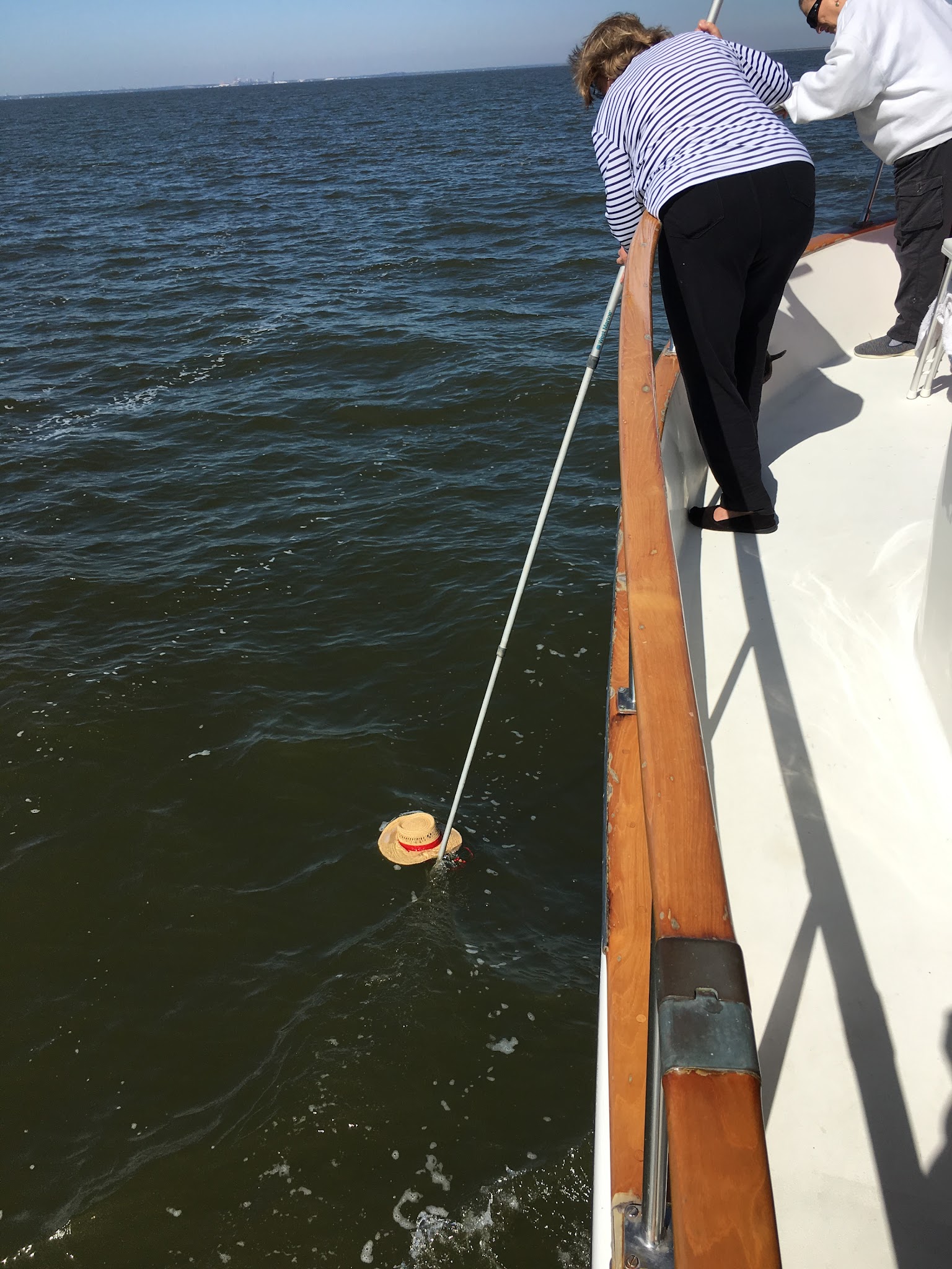 Debbie retrieving her hat from Mobile Bay beside Hunky Dory