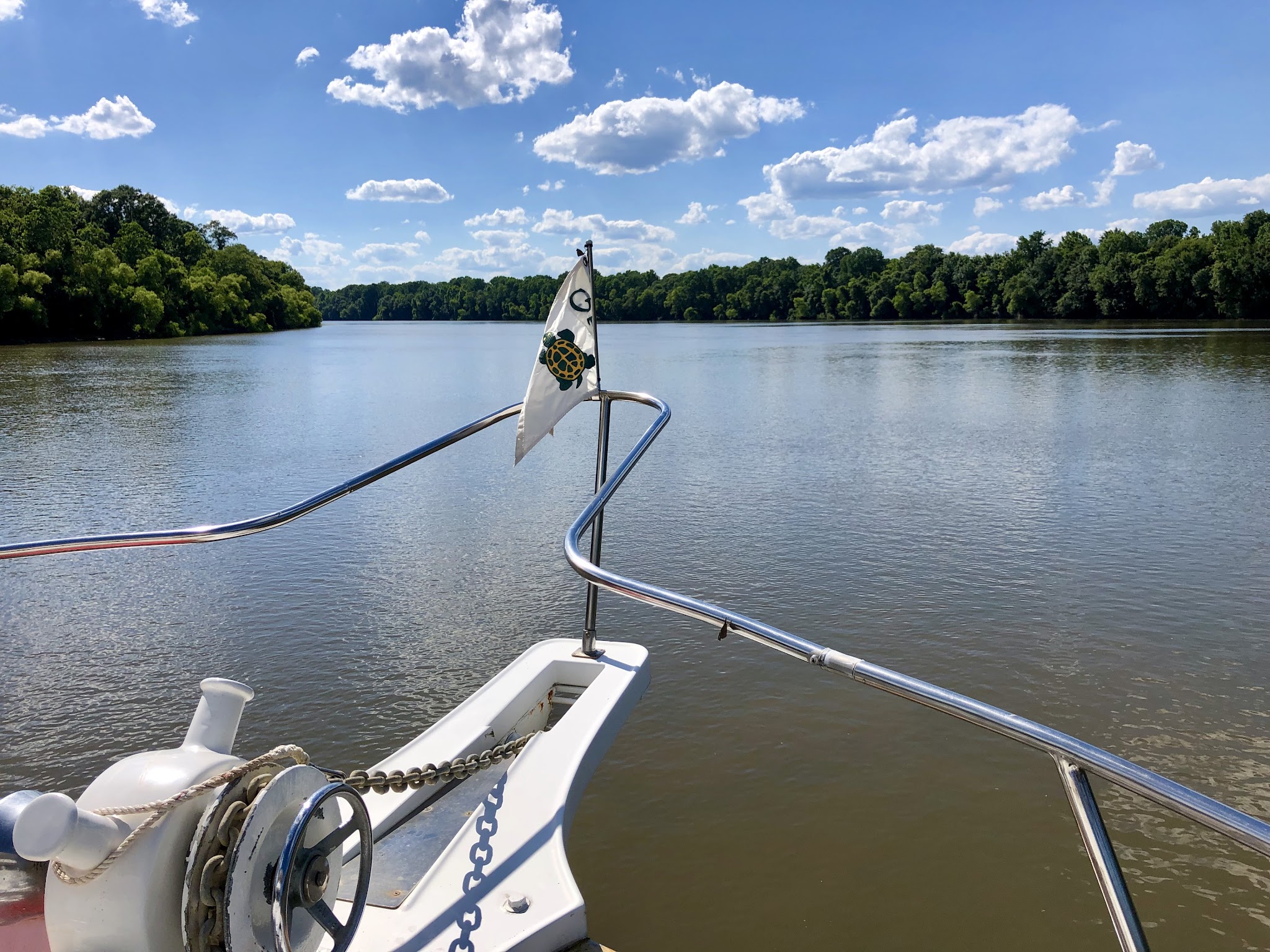 Hunky Dory’s bow and anchor gear facing a quiet, tree-lined stretch of the Tensaw River