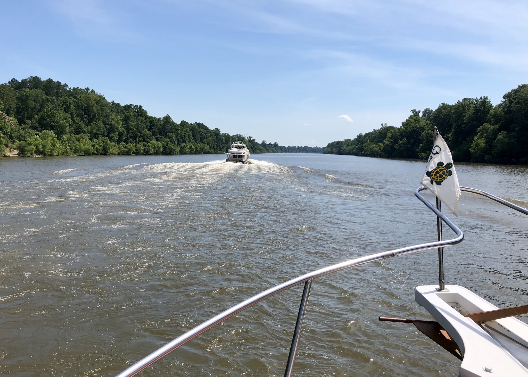 A cruising boat following Hunky Dory north on the tree-lined Tombigbee River
