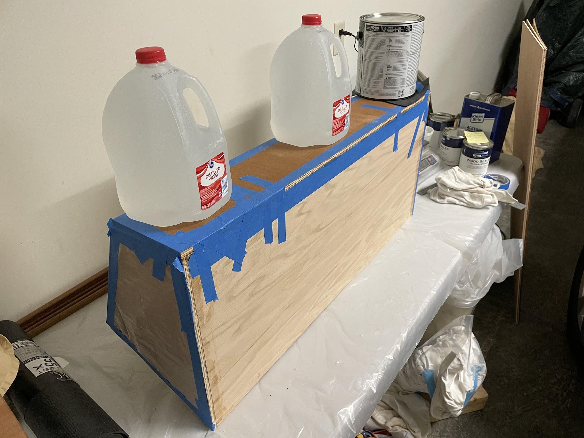 Water jugs and a paint can holding the console back panel while epoxy cures